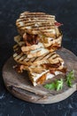 Stack grilled bacon, mozzarella sandwiches on wooden cutting boards on dark background, top view.Delicious breakfast