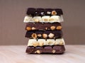 Stack of half chocolate bars with hazelnuts - milk chocolate, dark chocolate and white chocolate on wooden background Royalty Free Stock Photo