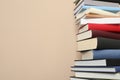 Stack of hardcover books on beige background. Space for text