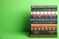 Stack of hardcover books on green background. Space for text