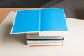 Stack of hardcover books with open blue book on top on light background Royalty Free Stock Photo