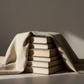 A stack of hardcover books is partially covered by a beige fabric cloth. The books are Royalty Free Stock Photo