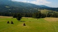 Stack of hay on a green meadow on hillside near the mountain village in sunset light Royalty Free Stock Photo