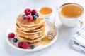 Stack of healthy oat pancakes with berries, honey and cup of green tea Royalty Free Stock Photo