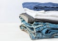 Stack Heap of Folded Jeans Cotton Pants Blue Shirts on White Wall Background. Closet Shelf. Eco Fashion Authentic Classic Style Royalty Free Stock Photo