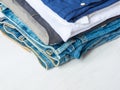 Stack Heap of Folded Jeans Cotton Pants Blue Shirts on White Wood Background. Closet Shelf. Eco Fashion Authentic Classic Style Royalty Free Stock Photo