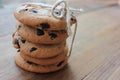 Stack of homemade chocolate chip cookies tied up with jute rope on wooden background. Christmas cookies gift on wood table.