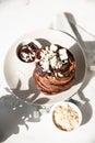 Stack of homemade chocolate pancakes with melted chocolate, ground almond and marshmallow, light background. Direct sunlight and