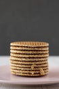 Stack of homemade Dutch stroopwafels with honey-caramel filling on pink plate, side view. Close-up