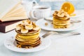 Stack of homemade pancakes with banana, maple syrup and walnuts on vintage plate.