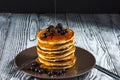 Stack of homemade pancakes with black currant and honey on brown plate on rustic background. Royalty Free Stock Photo