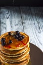 Stack of homemade pancakes with black currant and honey on brown plate on rustic background. Royalty Free Stock Photo