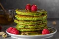 Stack of homemade pancakes with matcha tea, fresh raspberries, pistachios and honey on black background Royalty Free Stock Photo
