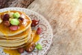 Stack of hot pancakes with nuts, dried fruits and caramel syrup.