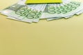 Stack of hundred euro bills partially hidden under green passport on yellow table Royalty Free Stock Photo