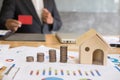 Stack of increasing coins and house model with businessman showing credit card. Investment in property, saving money for buying Royalty Free Stock Photo