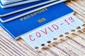 Stack of international passports with Inscription COVID-19 on wooden background. Coronavirus and travel concept. Closeup,