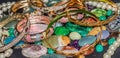 Stack of jewelry, gold bracelet, pearl necklace, and colorful gemstone.