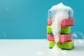 Stack of kitchen cleaning sponges with soap bubbles on blue background. Front view Royalty Free Stock Photo