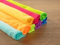 Stack of kitchen microfiber towels in bright colors on a brown wooden table