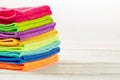 Stack of kitchen microfiber towels in bright colors on a white wooden background