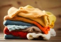 Stack of knitted clothes on wooden table opposite a defocused burlap background. Toned