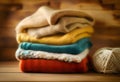 Stack of knitted clothes on wooden table opposite a defocused burlap background. Toned