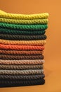 Stack of knitted material from multicolored threads on a orange background. Copy, empty space for text