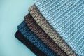 Stack of knitted material from threads of dark blue, light blue, gray colors on a blue background. Top view. Copy, empty space for