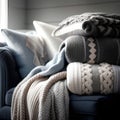 A stack of knitted sweaters on a blue sofa. Cozy home concept.