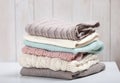 Stack of knitted textured clothing on table.Colorful winter clothes,warm apparel.Heap of knitwear