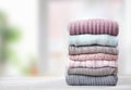 Stack of knitted textured clothing on table.Colorful winter clothes,warm apparel.Heap of knitwear