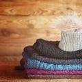 Stack of knitting colorful warm woolen clothes on wooden wall b