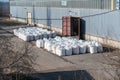 Stack of large bags next to a concealed industrial warehouse outdoors. Cargo handling and storage