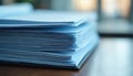 Stack of light blue documents rests on table. Policy documents, compliance implied. Image suggests business setting. Royalty Free Stock Photo