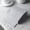Stack of Light Gray Paper Napkins on Countertop with White Cup and Saucer Royalty Free Stock Photo