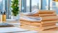 A stack of manila folders filled with paperwork sits on a desk in a modern office Royalty Free Stock Photo