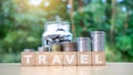 Stack many coins on a wooden block with a travel message.