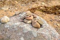 Stack of many small pebbles on top of the big grey round stone laying on pebble beach. Royalty Free Stock Photo