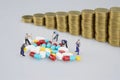 Stack of medicine with miniature people and blur coins Royalty Free Stock Photo