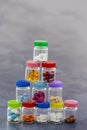 Stack of Medicine Tablets in glass Box with multi colored plastic caps on grey slate background Royalty Free Stock Photo