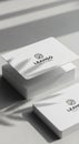Stack of minimalist business cards on a gray surface, featuring the logo \