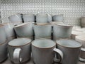 A stack of minimalist ceramic mugs displayed on a store shelf. Matte light-gray cups with subtle brown edging create a clean, Royalty Free Stock Photo
