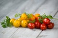 Stack of mixed cherry tomatoes orange, yellow and red with fresh herbs on a wooden background Royalty Free Stock Photo