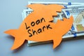 A stack of money and a paper fish with an inscription loan shark. Royalty Free Stock Photo