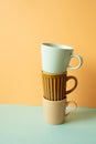 Stack of mug cup on mint green table. orange wall background. copy space Royalty Free Stock Photo