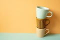 Stack of mug cup on mint green table. orange wall background. copy space Royalty Free Stock Photo