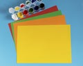 Stack of multi-colored paper and paint for drawing on a blue background. Royalty Free Stock Photo