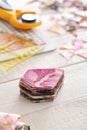 Stack of multi-colored pieces of fabric, ruler, cutting mat, rotary cutter on a white surface