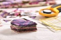 Stack of multi-colored pieces of fabric, ruler, cutting mat, rotary cutter on a white surface